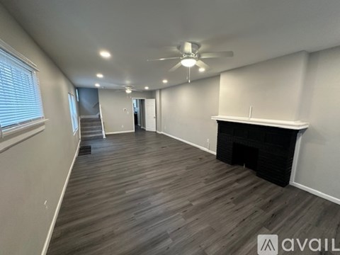 A spacious room with a fireplace and a ceiling fan.