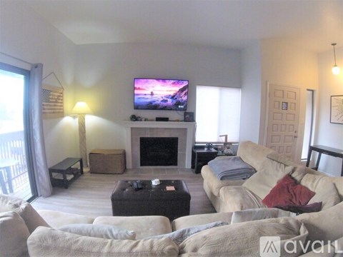 A living room with a large couch and a flat screen TV mounted above a fireplace.