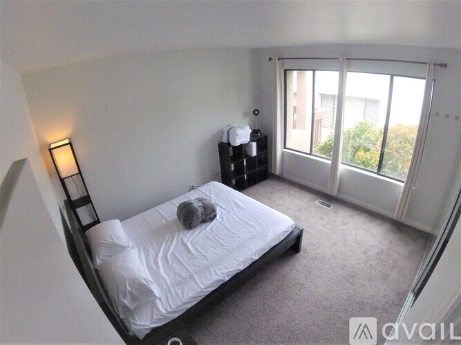 A bedroom with a bed, nightstand, and window.
