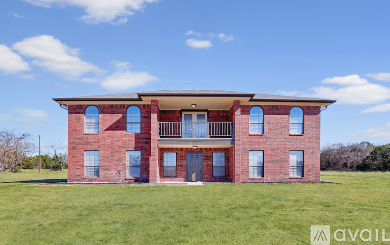 A red brick house with a balcony on the second floor.