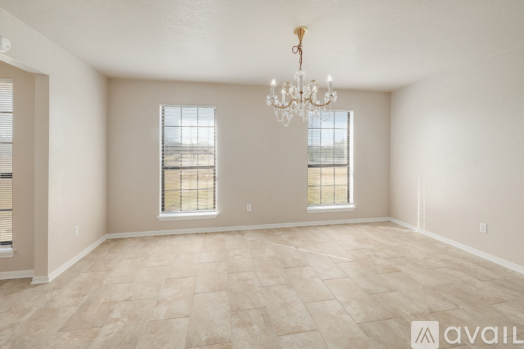A spacious room with a chandelier and two windows.