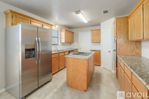 A kitchen with a stainless steel refrigerator and wooden cabinets.