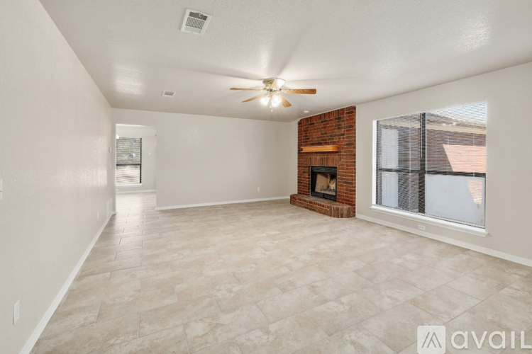 A spacious living room with a fireplace and a ceiling fan.