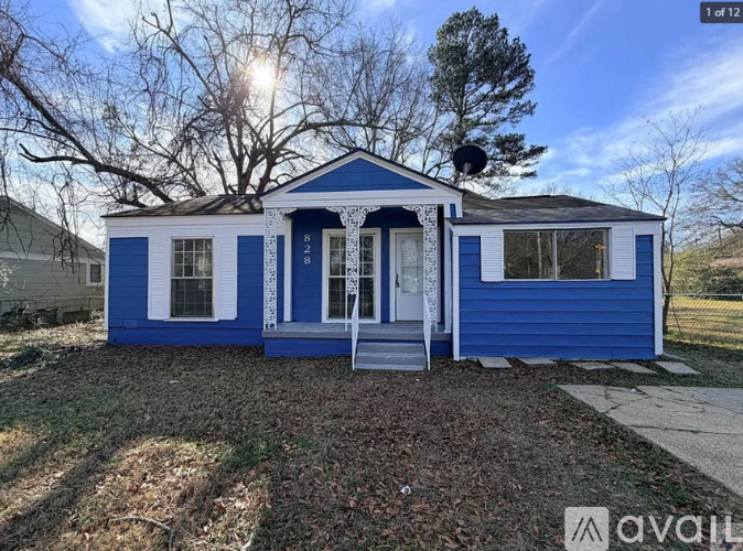 A blue and white house with a porch and a tree in the background.