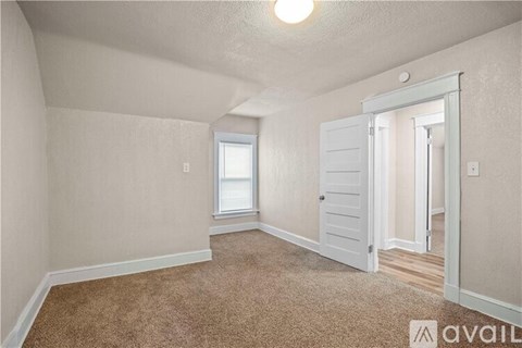 A room with a carpeted floor and a door leading to another room.