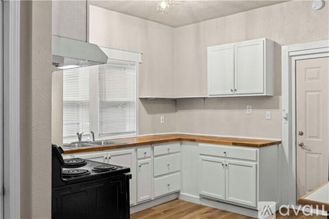 A kitchen with white cabinets and a black stove top oven.