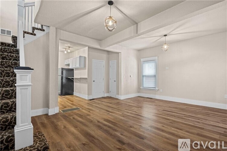 A spacious room with wooden flooring and a staircase with a patterned runner.