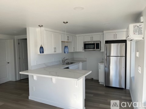 A kitchen with white cabinets and a marble island.