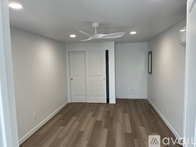 A room with a ceiling fan and wooden flooring.