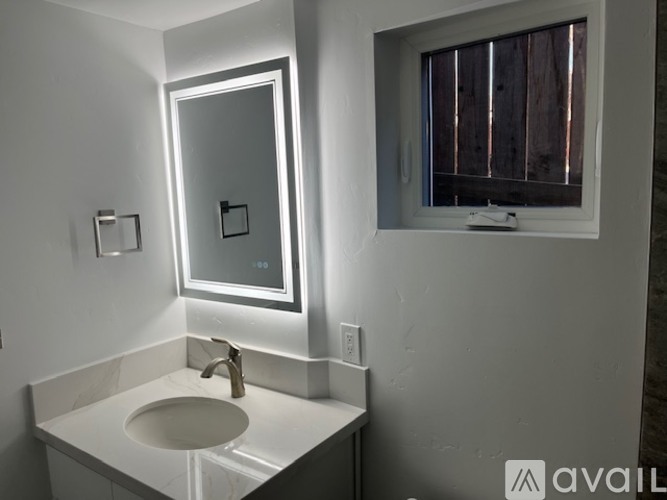 A bathroom with a sink, mirror, and window.