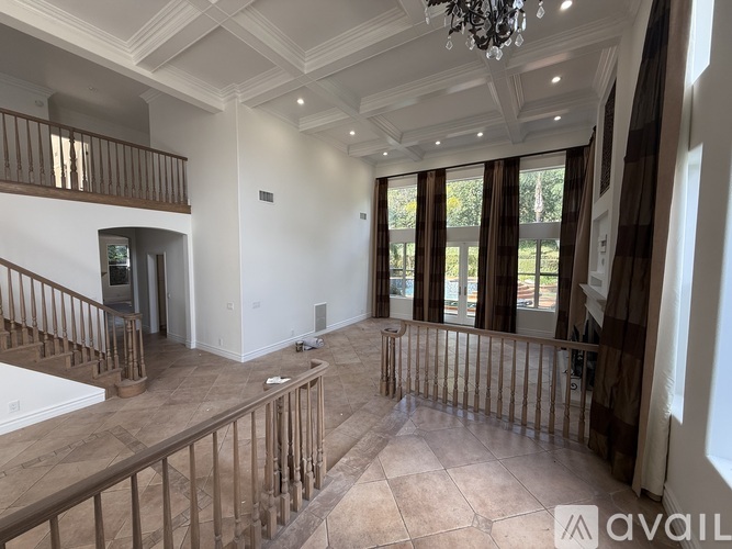 A spacious room with a staircase and a chandelier.