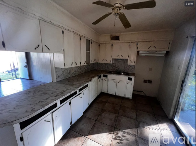 A kitchen with white cabinets and a ceiling fan.