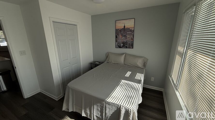 A bedroom with a bed, a door, and a picture on the wall.