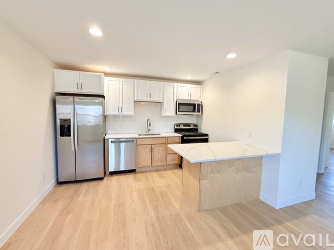 A kitchen with a refrigerator, microwave, oven, and sink.