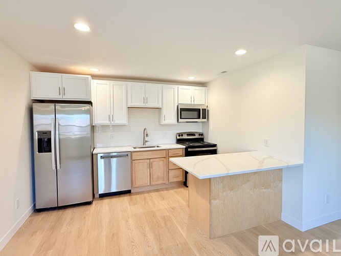 A kitchen with a refrigerator, microwave, oven, and sink.