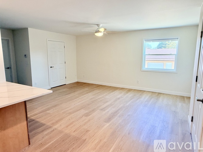 A room with wooden flooring and a window showing a building in the distance.