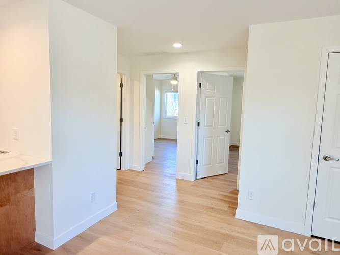 A spacious room with white walls and wooden flooring.