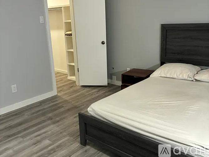 A bedroom with a bed, nightstand, and a closet with shelves.