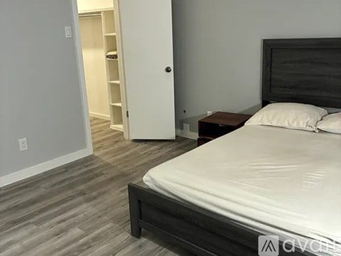 A bedroom with a bed, nightstand, and a closet with shelves.