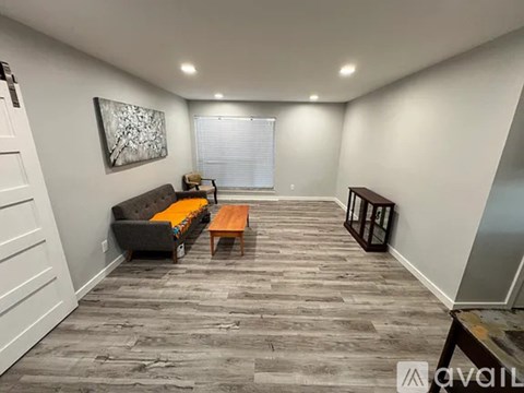 A living room with a grey couch, a wooden coffee table, and a painting on the wall.