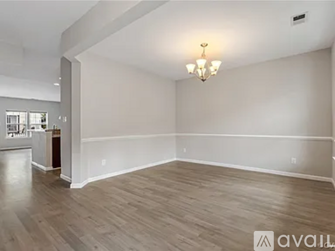 A spacious room with wood flooring and a chandelier.