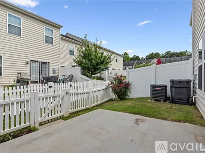 A white picket fence separates a driveway from a grassy area.