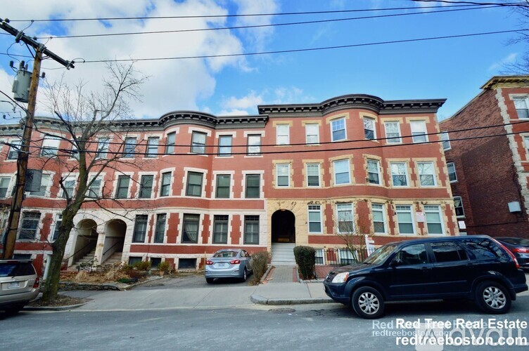 A large red brick building with a tree in front of it.