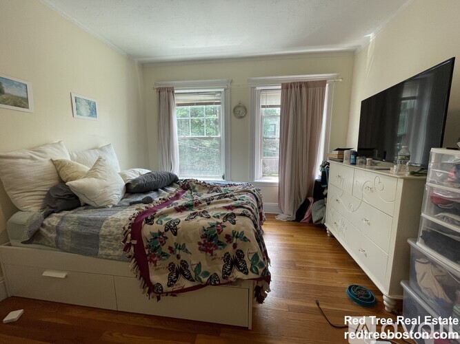 A bedroom with a bed, dresser, and window.