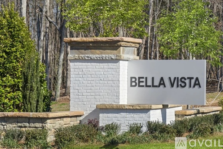 A sign that says "BELLA VISTA" in front of some trees.