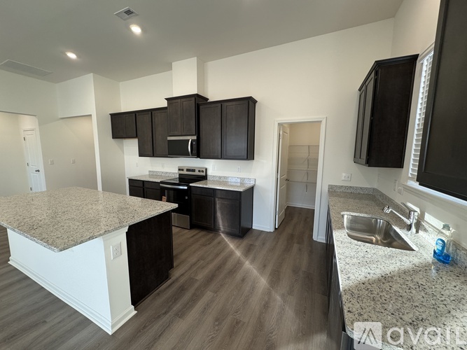 A kitchen with dark brown cabinets and a granite countertop.