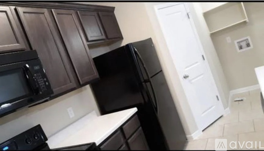 A kitchen with black appliances and brown cabinets.
