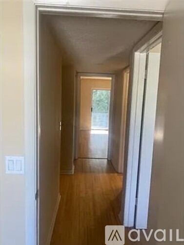 A hallway with a door on the left and a window on the right.