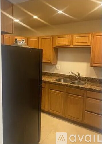 A black refrigerator in a kitchen with wooden cabinets.