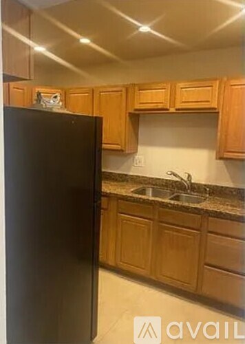 A black refrigerator in a kitchen with wooden cabinets.