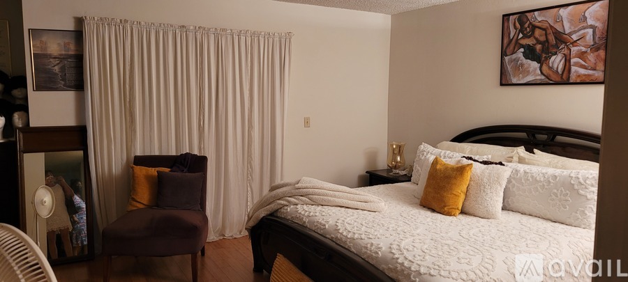 A bedroom with a large bed and a chair.