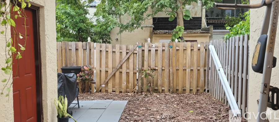 A backyard with a wooden fence and a red door.