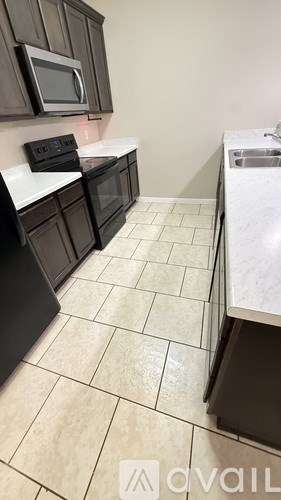A kitchen with black cabinets and white countertops.