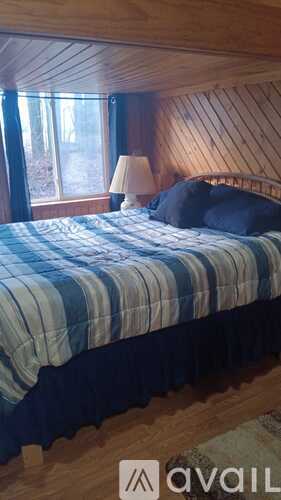 A bedroom with a bed, lamp, and window.