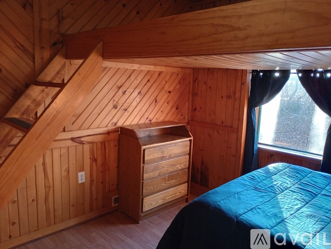 A bedroom with a bed, dresser, and window.