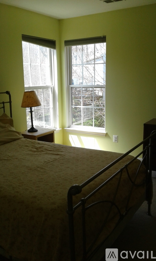 A bedroom with a bed, lamp, and window.