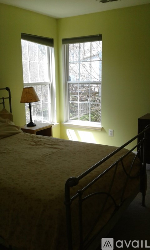 A bedroom with a bed, lamp, and window.