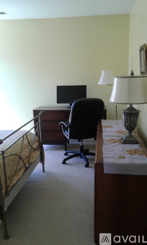 A bedroom with a bed, desk, chair, and lamp.