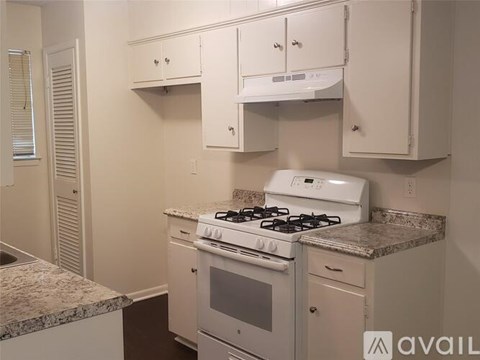 A kitchen with a white stove and cabinets.