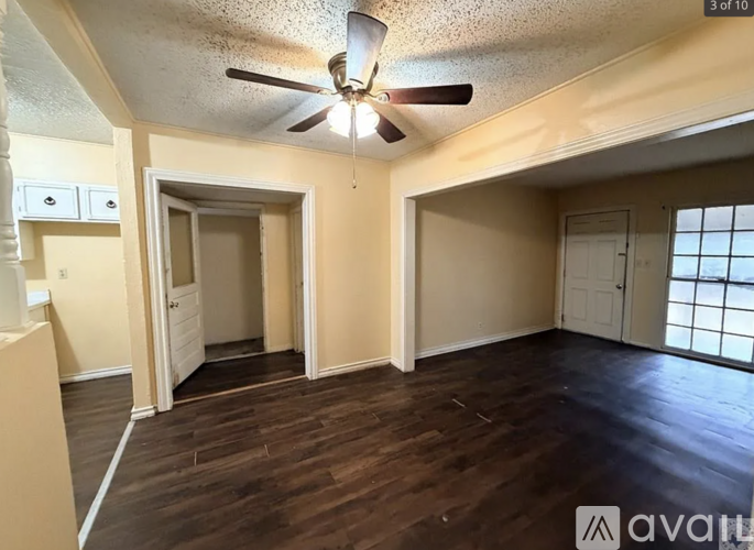 A room with a ceiling fan and wooden flooring.