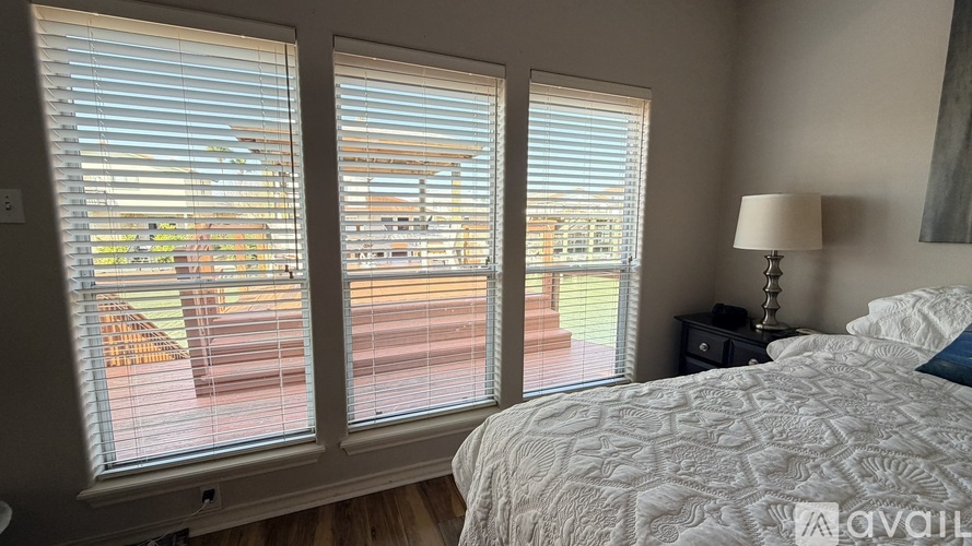 A bedroom with a large bed and a view of a house through the window.