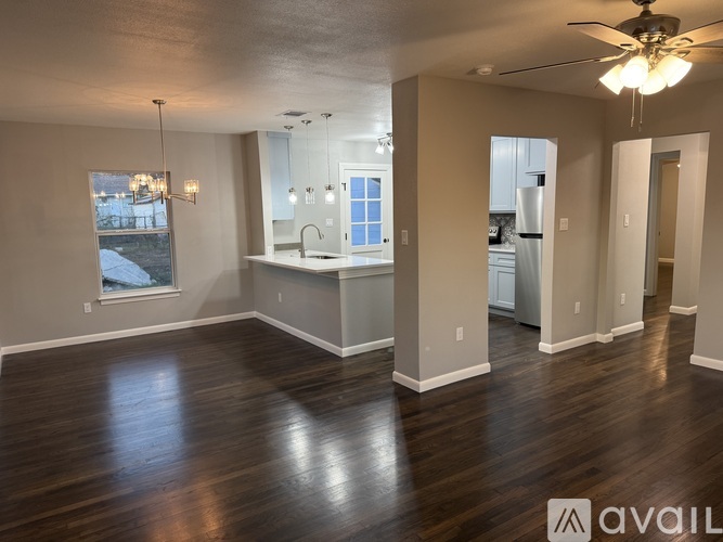 A spacious room with wooden floors and a ceiling fan.