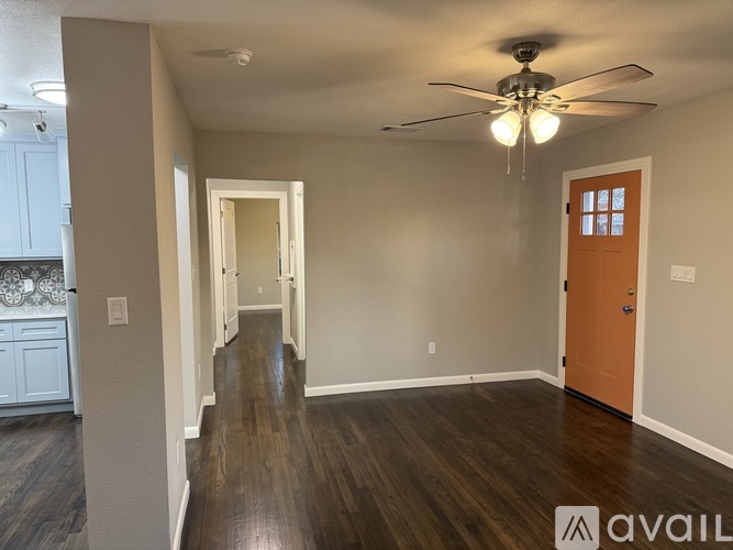 A room with a ceiling fan and wooden floors.