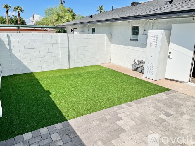 A backyard with a white fence and a green lawn.