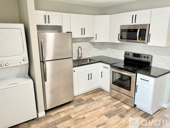 A kitchen with white appliances and wooden flooring.