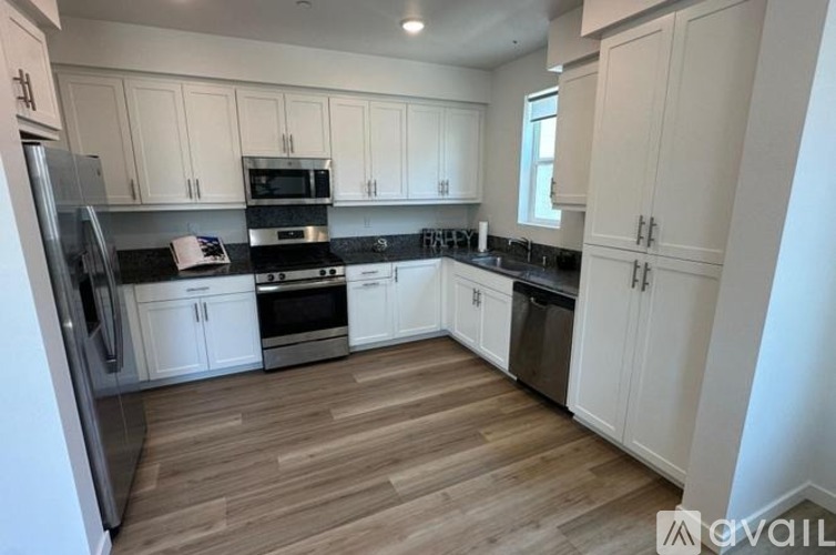 A kitchen with white cabinets and wooden flooring.